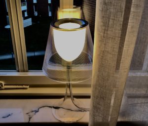 Modern bordslampa med genomskinlig skärm står på en fönsterbräda i ett seniorboende i Stockholm. En referenskund har fått professionell belysningskonsultation för att förbättra ljusmiljön i sitt boende.