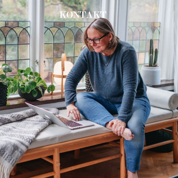 Kvinna i blå tröja och jeans sitter bekvämt och arbetar på en laptop i ett ljust rum omgivet av fönster och växter, med texten 'Kontakt' ovanför, vilket indikerar möjligheter till kommunikation och samverkan inom belysningskonsultation i Stockholm eller via webben.
